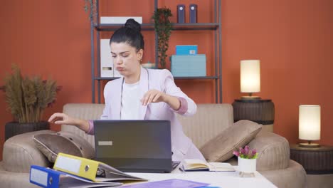 Home-office-worker-young-woman-finds-what-she-is-looking-for-on-the-table.